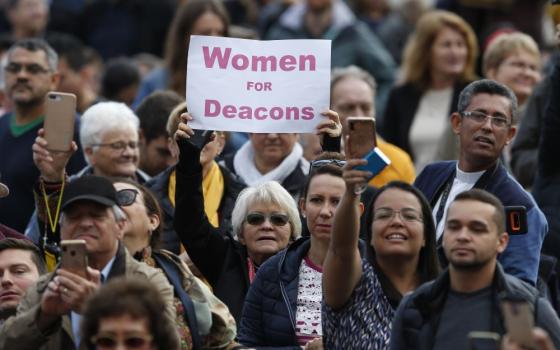 A woman holds a sign in support of women deacons as Pope Francis leads his general audience in St. Peter's Square at the Vatican Nov. 6, 2019. (CNS/Paul Haring)