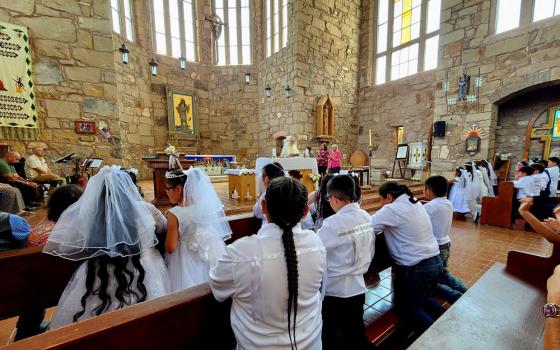 Fr. Dave Mercer, then-pastor of St. Joseph Apache Mission in Mescalero, New Mexico, stands at the altar during a first Communion Mass. Franciscan Br. Robert Lentz's icon "Apache Christ" adorns the wall behind Mercer. (Courtesy of Dave Mercer)