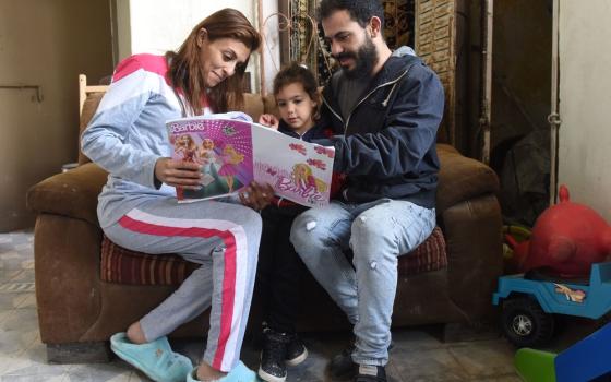 Man and woman read with little girl. 