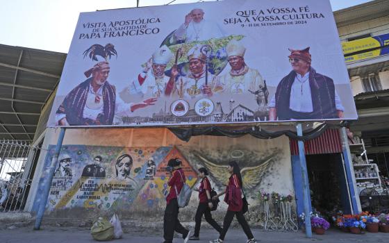 Billboard announcing Pope Francis' trip above mural of national heroes. 