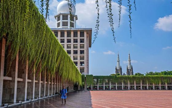 A man walks in the shade at Istiqlal mosque as the spires of the Our Lady of the Assumption Cathedral are seen in the background, in Jakarta, Indonesia, Aug. 9. (AP/Tatan Syuflana)