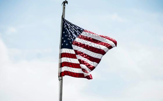 American flag flying against a blue sky with some white clouds (Unsplash/Andre Hunter)