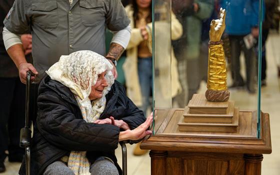 A woman presses her hand against a glass case protecting a reliquary containing a bone from the arm of St. Jude the Apostle at St. Jude Church in Mastic Beach, N.Y., Nov. 27, 2023. The relic, which arrived in Chicago from Italy in September,was on a nine-month tour of the U.S. (OSV News/Gregory A. Shemitz)