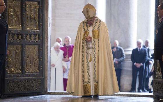 Pope Francis prays after walking through the Holy Door to inaugurate the Jubilee Year of Mercy in St. Peter's Basilica at the Vatican in this Dec. 8, 2015, file photo. In the background at left is retired Pope Benedict XVI. The pope has approved the theme, "Pilgrims of Hope," to be the motto for the Holy Year 2025. (CNS/Vatican Media)