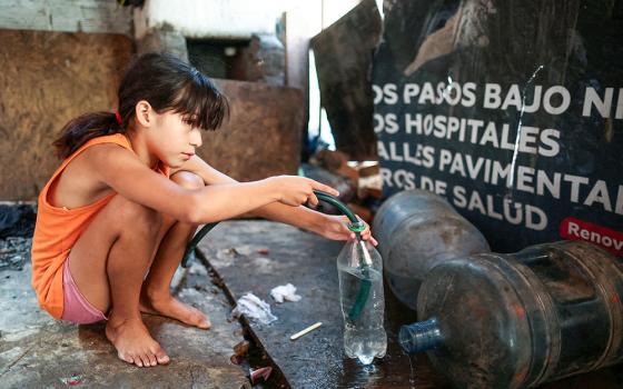 A girl fills a bottle with a hose to bring drinking water to her home in a poor section of Buenos Aires, Argentina, Feb. 27, 2024. (OSV News/Reuters/Agustin Marcarian)