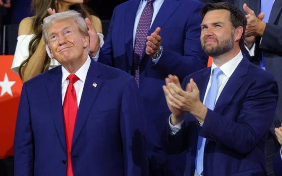 Trump and Vance stand looking up and smiling.