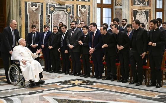 Seminarians in black lined up as Francis enters in wheelchair.