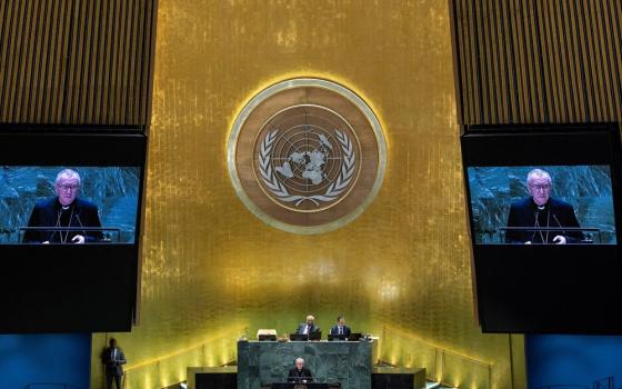 Large United Nations emblem and projector screens showing Parolin speaking.