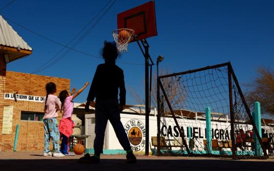 Three young girls play basketball outdoors. 