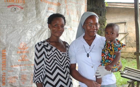 Sr. Janefrances Ihekuna poses for a photo with a nursing mother and her baby after testing them for malaria and HIV during their free medical outreach in the community.