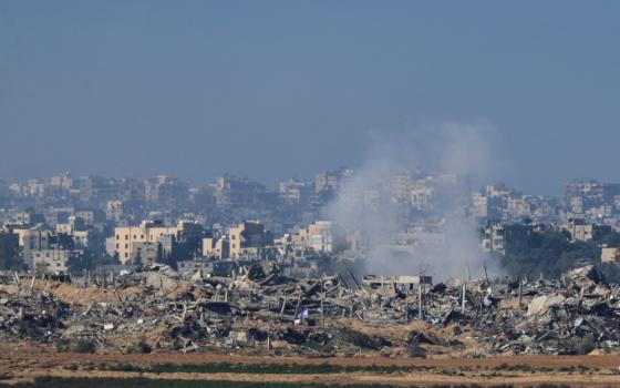 An Israeli flag flies next to the rubble of destroyed buildings Dec. 26, 2023, as smoke rises in the Gaza Strip, as seen from southern Israel.