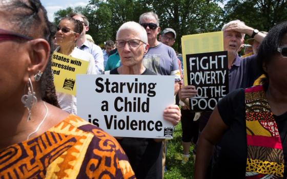 Marie Dennis holds sign at protest.