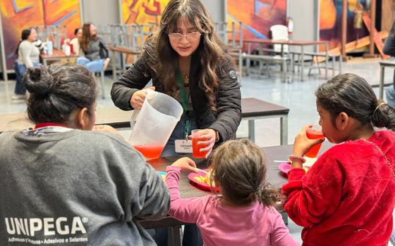 Sophomore Victoria Mendoza-Cardena, 16, from Sacred Heart Preparatory in Atherton, California, serves a Central American mother and her two young daughters breakfast on Feb. 19, 2025, at the Kino Border Initiative in Nogales, Mexico. (Anita Snow)