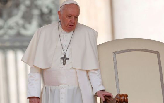 Pope Francis holds onto the arm of his chair as he arrives for the general audience in St. Peter's Square at the Vatican April 20. Since February, the pope, who has long suffered from sciatica, has repeatedly had difficulty walking, resulting in a number 