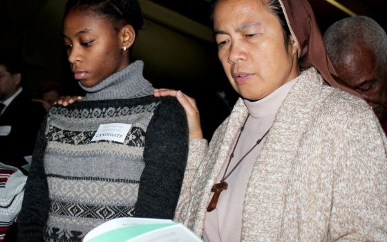 A religious sister places her hand on the shoulder of a candidate during the Rite of Election and Call to Continuing Conversion ceremony in the Diocese of Brooklyn in the 2016 file photo. (CNS/The Tablet/Marie Elena Giossi)