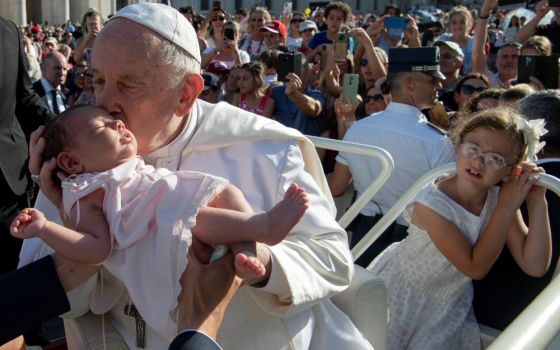 Pope Francis kisses a baby before attending Mass in St. Peter's Square during the World Meeting of Families at the Vatican June 25. The event usually takes place every three years, but it was not held last year because of the COVID-19 pandemic. 