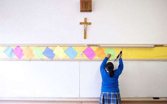 This July 18, 2012, file photo shows a student stapling colored paper to the wall of a classroom after summer school at Our Lady of Lourdes in Los Angeles. (AP Photo/Grant Hindsley)