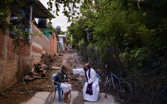 Rev. Gilberto Vergara blesses a person giving confession in Aguililla in the Michoacan state of Mexico, Friday, Oct. 29, 2021. (AP Photo/Eduardo Verdugo)