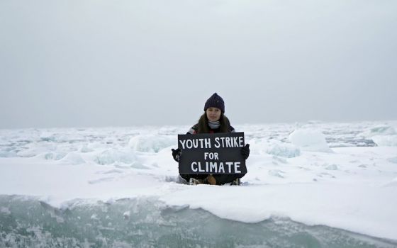 Environmental activist and campaigner Mya-Rose Craig, 18, holds a cardboard sign reading "youth strike for climate" as she sits on the ice floe in the middle of the Arctic Ocean, hundreds of miles above the Arctic Circle, Sept. 20. (CNS/ Reuters/Natalie T