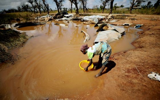 A woman collects water for washing as floodwaters begin to recede in the aftermath of Cyclone Idai near Beira, Mozambique, in March. (CNS/Reuters/Mike Hutchings)