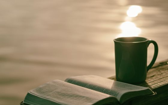 Coffee cup sits next to open Bible.