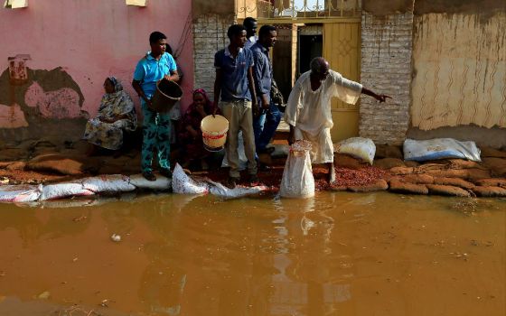 Men stand in floodwaters following heavy rains in Khartoum, Sudan. East Africa is struggling under a cascade of impacts from torrential rains, locusts and the coronavirus pandemic. (CNS photo/Mohamed Nureldin Abdallah, Reuters)