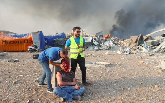 An injured man is aided following explosions at the Beirut, Lebanon, port on Aug. 4, 2020. (CNS photo/Mohamed Azakir, Reuters)