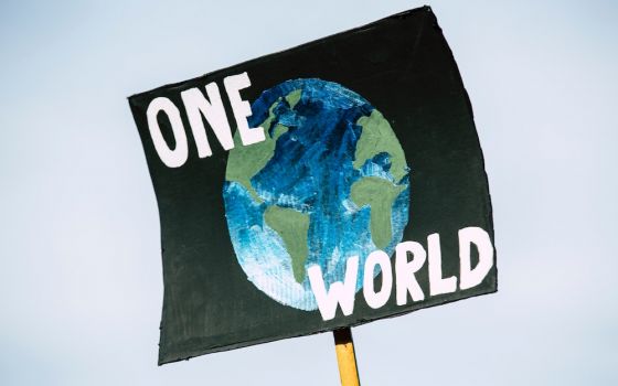 Sign showing planet and words "One World' (Unsplash/Markus Spiske)