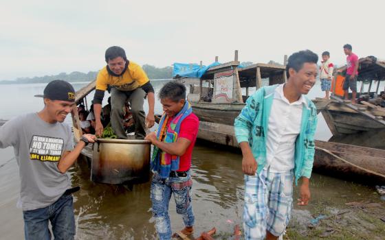 Men in a community on the Marañón River in Peru's Amazon region unload a pot of water they have drawn from the middle of the lake, the community's main water source. (Photo by Barbara Fraser)