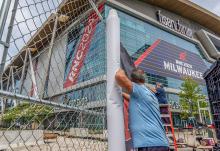 Workers attach signage to security fencing on July 10, ahead of the 2024 Republican National Convention at the Fiserv Forum in Milwaukee. (AP/Alex Brandon)