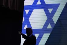 Trump silhouetted against illuminated stage background of the Star of David. 