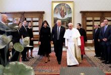 Trump walks center, to his left is Pope Francis, and to his right is Melania.