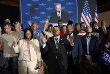 People stand with their hands raised, behind is a projector screen showing Graham.