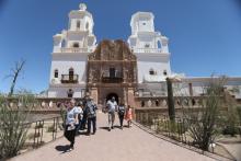 People walk out of large mission style church.